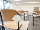 Empty classroom desks with mask hanging on a chair